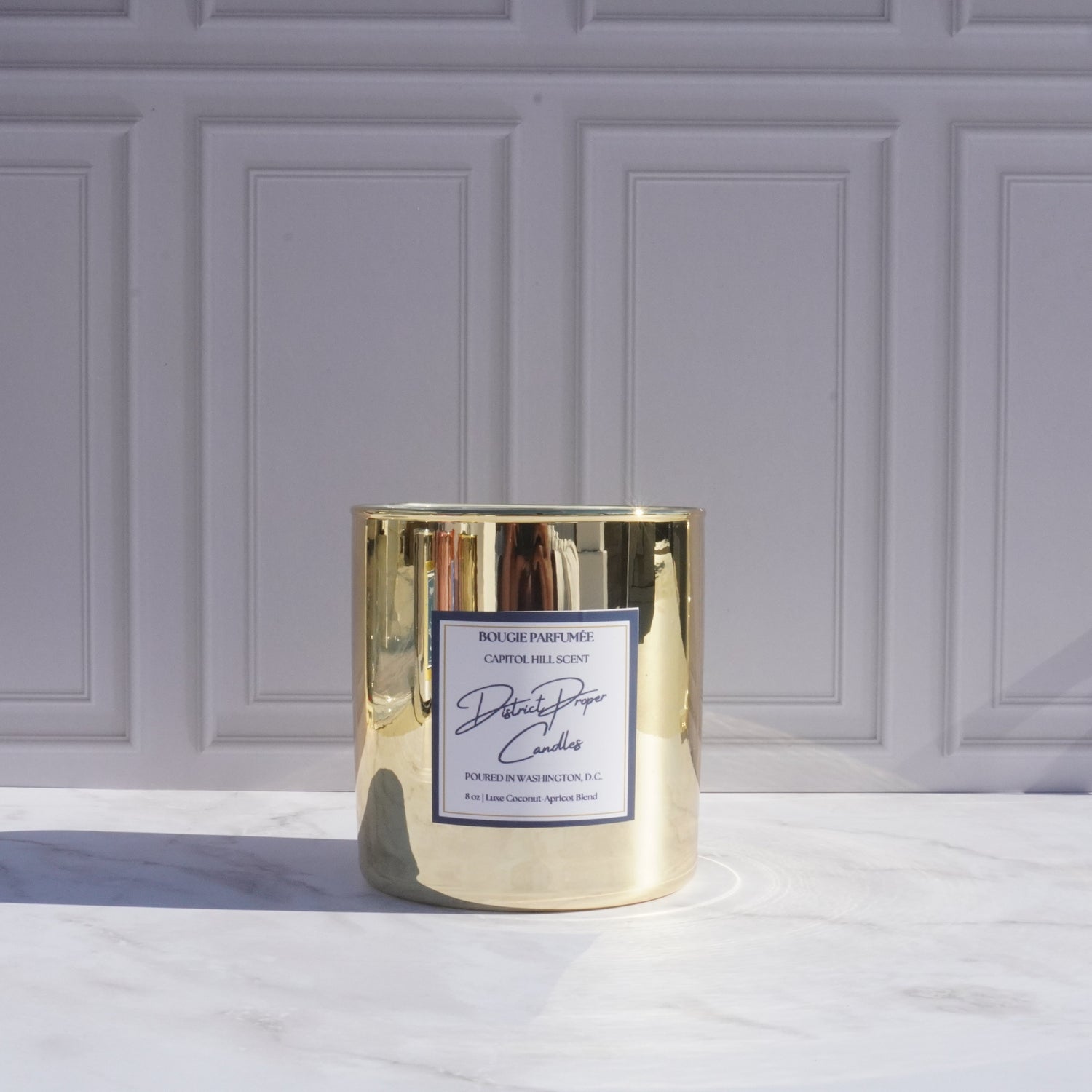 Gold candle with luxury packaging. Capitol Hill premium candle in coconut apricot wax. Smells like rich amber.
