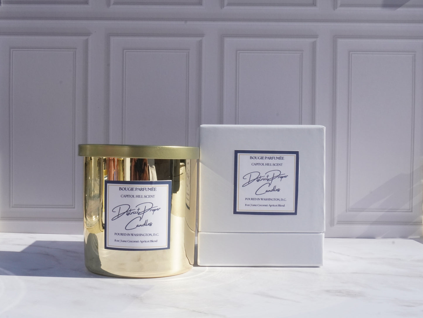 Gold candle with luxury packaging. Capitol Hill premium candle in coconut apricot wax. Smells like rich amber.