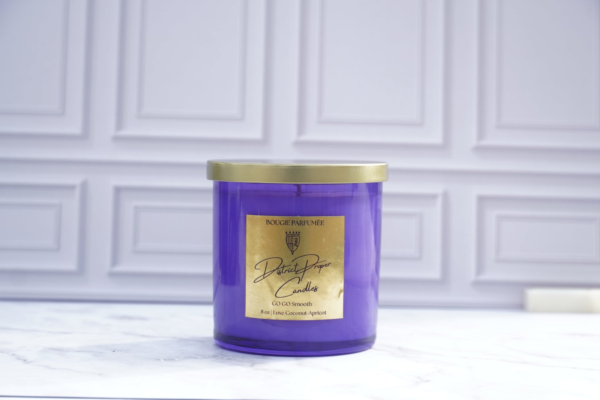 Purple candle with gold lid. GoGo Smooth luxury candle handpoured in a luxurious coconut apricot wax. Candle smells like driftwood, clean rouge, hint of spice.