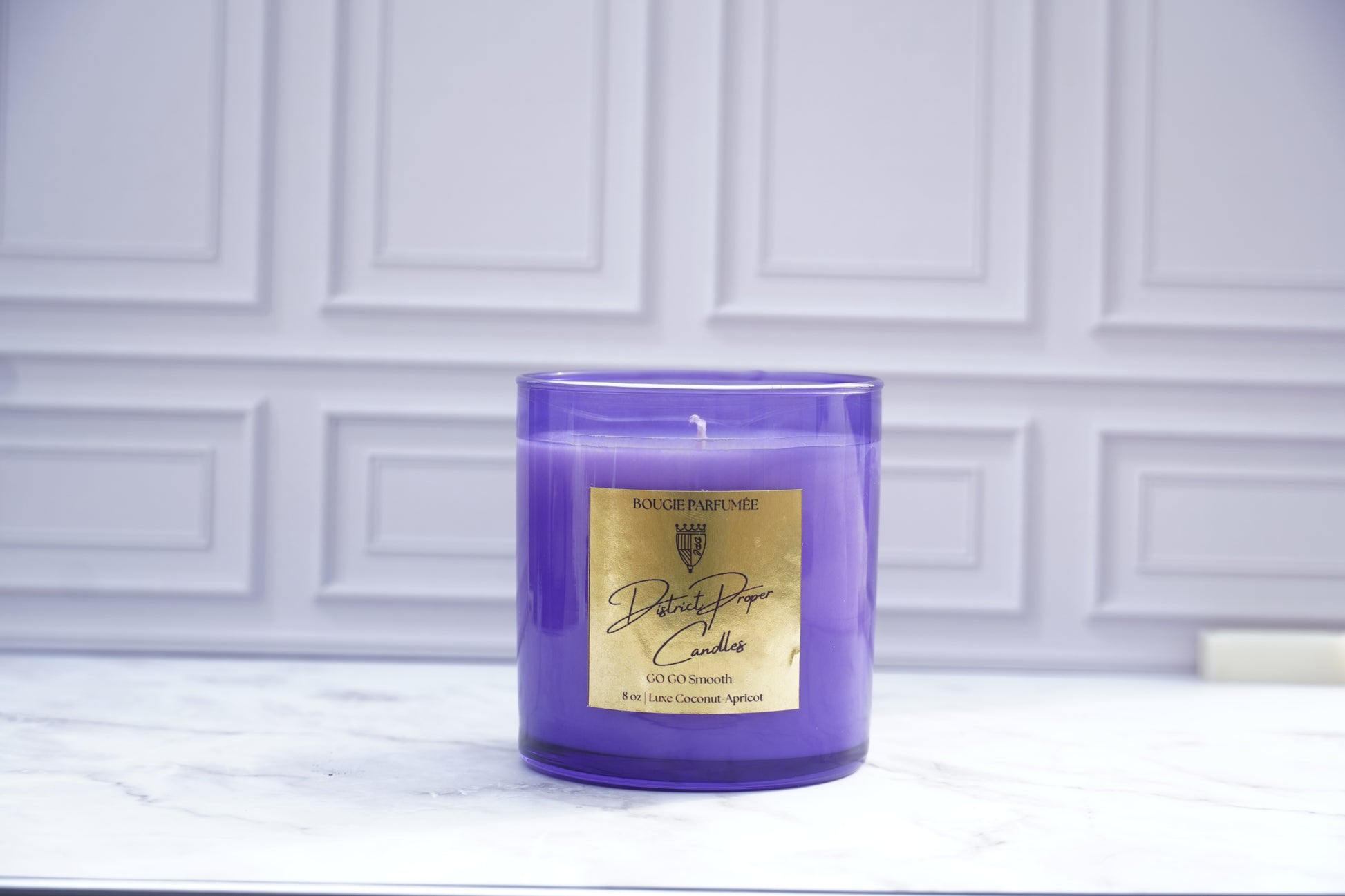 Purple candle with gold label. Handpoured in coconut apricot wax. Smells like driftwood and cashmere.