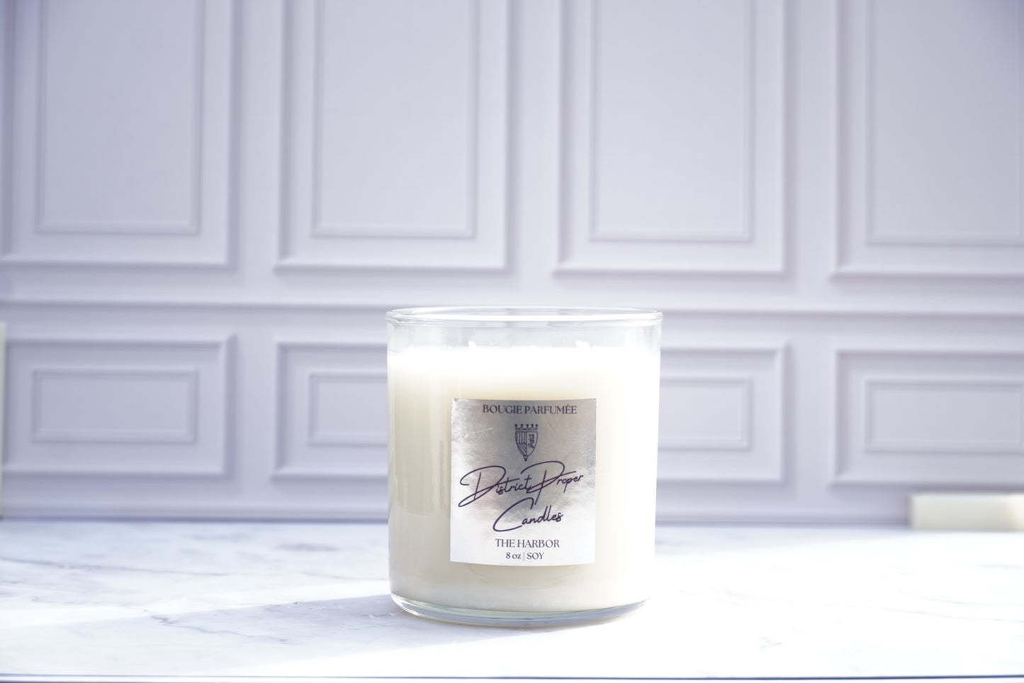 Candle and its packaging on white marble surface. Harbor candle handpoured in soy wax. Smells like citrus, ocean breeze and clean fragrance.